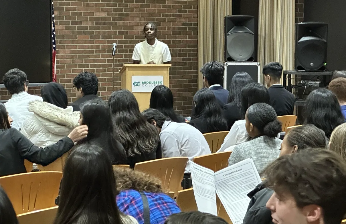 Student speaking at a podium to a large audience